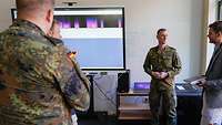 Ein Soldat erklärt vor einem Smartboard stehend den Zuhörenden ein IT-System. 