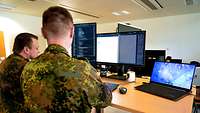 Zwei Soldaten sitzen an einem Computer und programmieren.