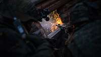 Ein Soldat mit Gewehr schießt aus einem Schützenloch in einer Wand. Ein Lichtblitz entsteht.