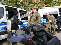 Soldaten und Polizisten tauschen sich im Gespräch aus. Im Hintergrund ein Polizeibus.
