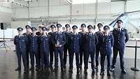 14 Soldaten in blauer Uniform stehen für ein Gruppenbild in einer Halle.