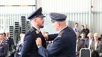 Der Inspekteur der Luftwaffe überreicht einem Absolventen das Tätigkeitsabzeichen für Militärluftfahrzeugführer.