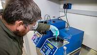 Ein Soldat füllt im Labor Kraftstoff mittels einer Spritze in ein Messgerät zur Überprüfung der Qualität.