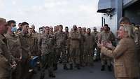 Die Wehrbeauftragte steht vor einer Gruppe von Soldaten in Uniform auf dem Flugdeck und gestikuliert
