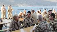 Die Wehrbeauftragte sitzt mit Soldatinnen und Soldaten an einem Holztisch und führt Gespräche