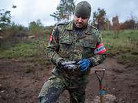 Ein Soldat steht auf einem Truppenübungsplatz und hält in seinen Händen einen Splitter einer gesprengten Granate.