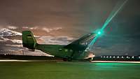 Abends steht ein Flugzeug auf einem Rollfeld. Die Spitze einer Tragfläche leuchtet grün.