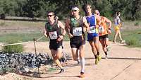 Mehrere Sportler kämpfen um die Führung beim Crosslauf.