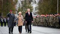 General Zorn, Ministerin Lambrecht und ein Mann in langer schwarzer Jacke schreiten angetretene Soldaten ab