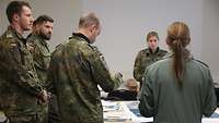 Soldaten und Soldatinnen umringen einen Planungstisch mit Karten und Informationsmaterial.