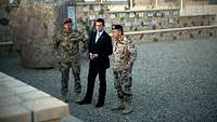Zwei Generale und der Verteidigungsminister zu Guttenberg stehen vor einem großen Stein in Afghanistan