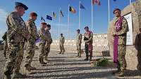Mehrere Soldaten stehen bei einer Gedenkfeier vor einem großen Gedenkstein