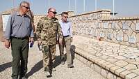 Der Verteidigungsminister de Maiziére geht mit einem Soldaten an einer Gedenkmauer lang 