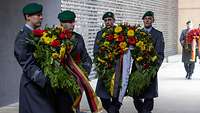 Soldaten vom Wachbataillon tragen Blumenkränze ins Ehrenmal der Bundeswehr.