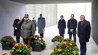 Ministerin Lambrecht und weitere Personen stehen vor Blumenkränzen im Ehrenmal der Bundeswehr.