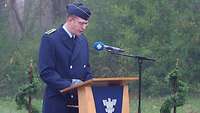 Stabsfeldwebel Gott steht in blauer Uniform am Rednerpult.