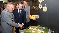 Ministerpräsident Kretschmer schneidet zusammen mit einem Soldaten einen Bundeswehr-Kuchen an.