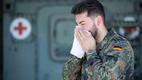 Ein Soldat benutzt ein Taschentuch für seine Nase