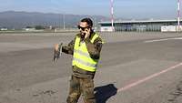 Ein Soldat in Warnweste telefoniert auf einem Flugfeld