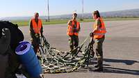 Zwei Soldaten und eine Soldatin bereiten ein Gepäcknetz vor