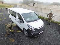 Ein Soldat untersucht mit Hilfe einer Teleskopstange, an der sich ein Spiegel befindet, den Unterboden eines Transporters ab