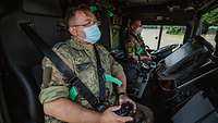 Zwei Soldaten sitzen in einem Fahrzeug namens elektronische Deichsel. Einer der Soldaten hält einen Controller in der Hand.