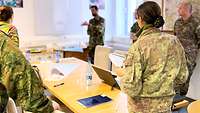 Soldiers from different nations standing around a table in discussion.