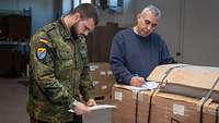 Ein Soldat und ein Zivilist kontrollieren Papiere und den Wareneingang.