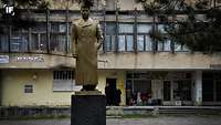 Eine bronzene Stalin-Statue steht vor einem verfallenen Gebäude