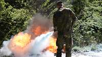 Ein Soldat nutzt einen Feuerlöscher um ein von der Feuerwehr gelegtes Feuer zu löschen. 