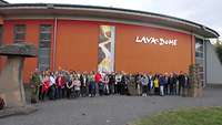 Gruppenfoto vor einer lavaroten Außenwand des Museums.