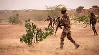 Nigrische Soldaten überqueren eine Freifläche