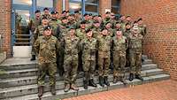 Gruppenfoto von Soldaten gestaffelt auf einer Treppe vor einem Backsteingebäude