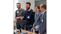 4 Seminarteilnehmende stehen an einem Tisch vor einem Lego Serious Bauwerk