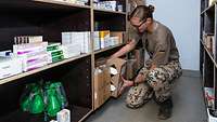 Eine Soldatin sortiert Medikamente und Sanitätsmaterial in Regale