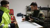 Ein Soldat steht in der Waffenkammer und empfängt sein Gewehr. 