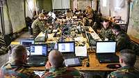 Ein Zelt mit Soldaten unterschiedlicher Nationen vor Computern