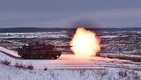 Ein Leopard 2 Kampfpanzer schießt in verschneiter Landschaft, rechts ein Lichtblitz