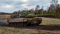 Ein Kampfpanzer Leopard 2 A6 fährt auf einem matschigen Weg.