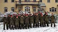 Gruppenfoto zahlreicher Soldatinnen und Soldaten vor einem historischen Gebäude. Es liegt Schnee.