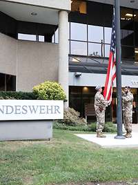 Service members hoist the American flag in front of the building of the Office of Defense Administration, U.S.A. and Canada