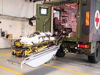 Ein militärisches Sanitätsfahrzeug in einer Halle. Der Tragentisch ist ausgefahren
