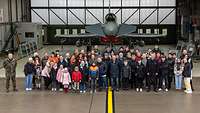 Eine Gruppe von Menschen steht, für ein Gruppenbild, vor dem Jagdflugzeug vom Typ Eurofighter