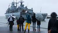 Ein Kriegsschiff im Hafen wird von Familienangehörigen verabschiedet