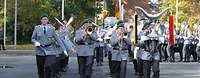 Military musicians march along a street playing music