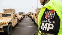 A soldier stands next to a column of vehicles