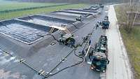 Large tanks and in front of them two tank trucks from the Bundeswehr that are being refueled