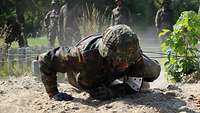 Soldier in combat suit slides on the obstacle course