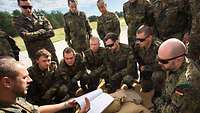 A soldier explains something on a notebook to a group of soldiers