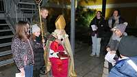 Der Nikolaus versammelt sich mit Kindern und sie warten auf Geschenke.